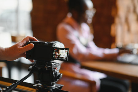 Young blogger with laptop recording video on camera at cafeの写真素材