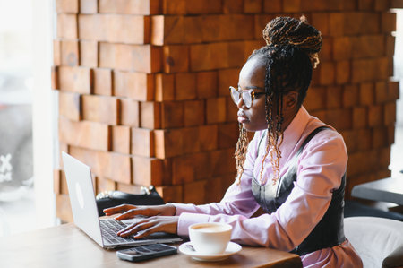 Portrait of smart young woman with mobile phone working on laptop at outdoor coffee shop.の写真素材