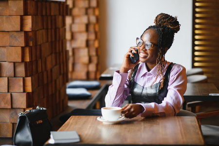 Young african woman using smart phone in a modern cafe.の写真素材