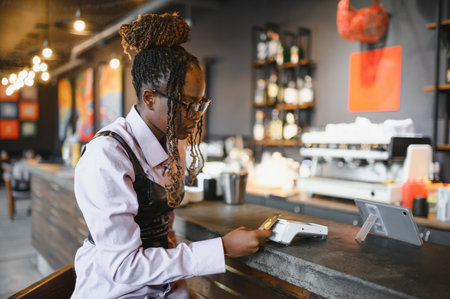 Customer is holding her smartphone near a payment terminal to make a contactless payment for her...
