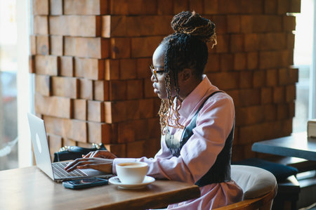 Portrait of an African American young woman sitting at cafe with laptop writing her blog.の写真素材