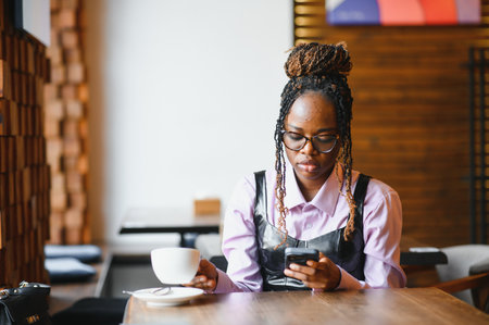 Young african woman using smart phone in a modern cafe.