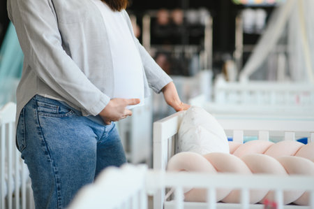 Happy pregnant woman choosing a baby crib in the store.