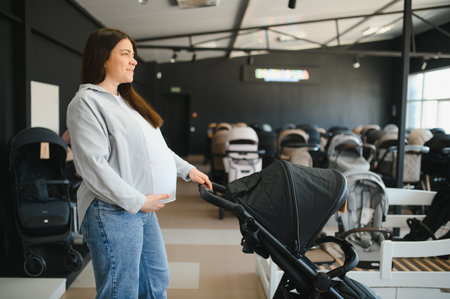 young pregnant woman choosing pram for newborn in infant shop.