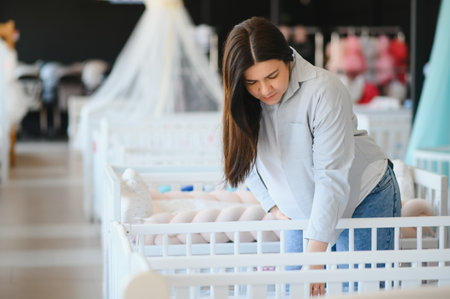 Happy pregnant woman choosing a baby crib in the store.
