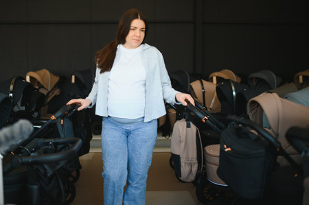 Pregnant woman choosing baby stroller at store. Mother doing shopping in baby shop. Baby trollers...