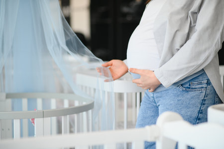 Pregnancy shopping concept. Pregnant woman choosing cradle cot or crib for newborn at baby shop...