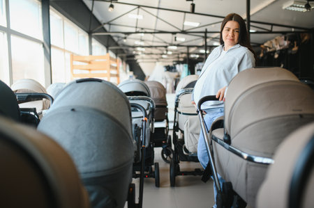 young pregnant woman choosing pram for newborn in infant shop.の写真素材