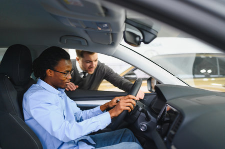 A consultant at a car dealership helps a customer choose a new car.