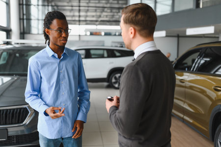 Portrait of male client talking to professional car dealer in dealership. Concept of choosing and buying new auto.の写真素材