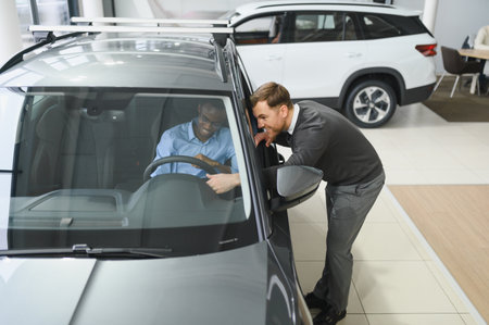 A consultant at a car dealership helps a customer choose a new car.の写真素材