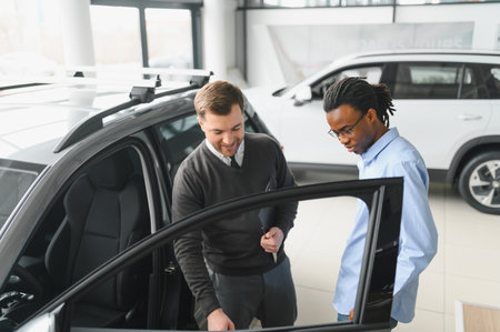 A consultant at a car dealership helps a customer choose a new car.の写真素材