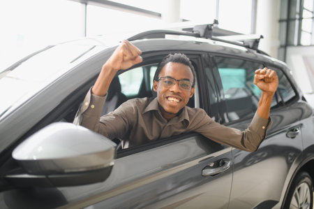 Young handsome man choosing a car in a car showroom.