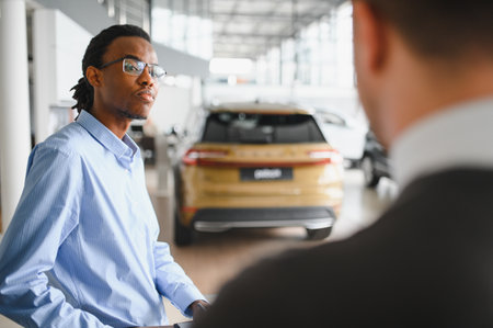 Dealer with male customer signing documents at auto salon. Bearded man in buying new vehicle at car center.の写真素材