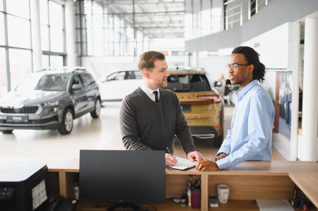 Dealer with male customer signing documents at auto salon. Bearded man in buying new vehicle at car...