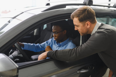 Car Sales Manager Showing Auto To Buyer Standing In Luxury Automobile Dealership Store.の写真素材