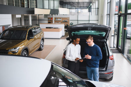 Car Sales Manager Showing Auto To Buyer Standing In Luxury Automobile Dealership Store.の写真素材