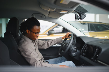 Young African American man is choosing a new vehicle in car dealership.の写真素材