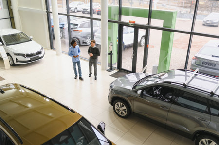 Male car dealer helps customer choose car in car dealership. Man buys new car.の写真素材