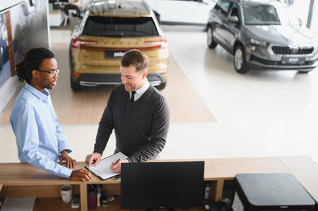 manager car salesman in car dealership signing contract at table with male buyer.の写真素材