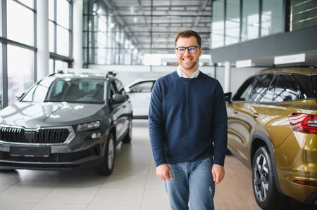 Young man is choosing a new vehicle in car dealership.