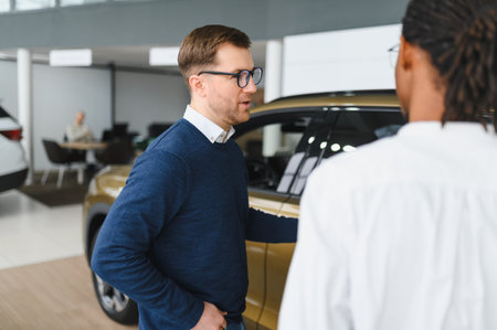 A consultant at a car dealership helps a customer choose a new car.の写真素材
