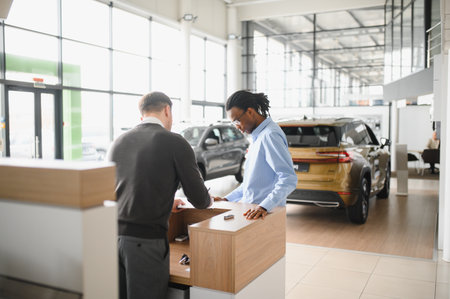 manager car salesman in car dealership signing contract at table with male buyer.の写真素材