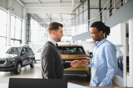 A consultant at a car dealership helps a customer choose a new car.の写真素材