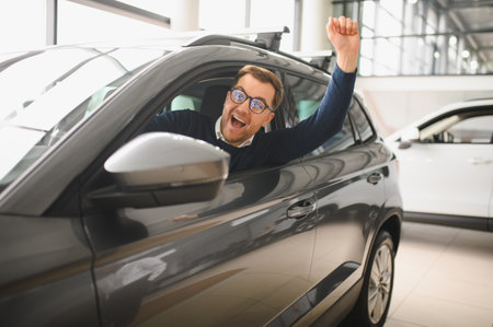 Young man is choosing a new vehicle in car dealership.の写真素材
