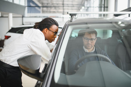 Car Sales Manager Showing Auto To Buyer Standing In Luxury Automobile Dealership Store.の写真素材
