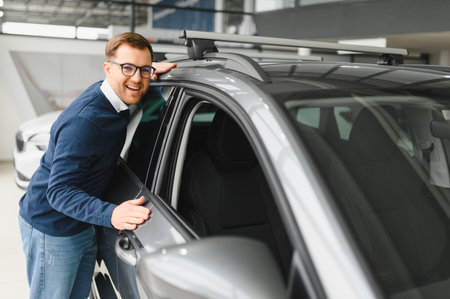 Young man is choosing a new vehicle in car dealership.