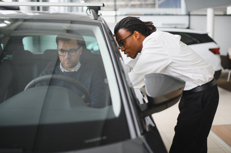 A consultant at a car dealership helps a customer choose a new car.の写真素材