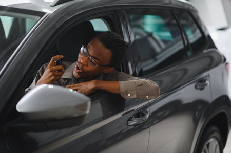 Young African American man is choosing a new vehicle in car dealership.の写真素材