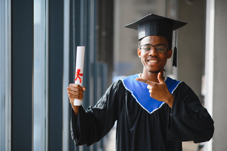 Smiling african american medical student showing his diploma while wearing his graduation gownの写真素材