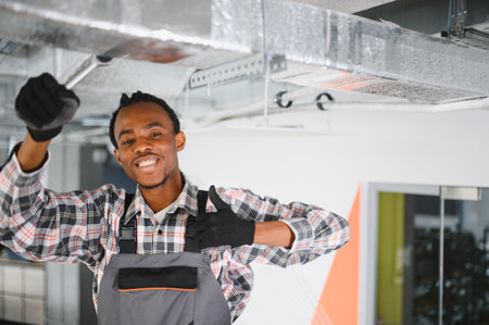 African american technician expertly maintaining an air conditioning unit, showing professional skills in hvac repair and ventilation systemsの写真素材