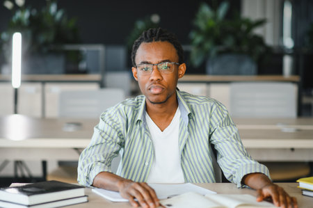 Dedicated african american student studying diligently with books and notes, preparing for graduation in a modern university settingの写真素材