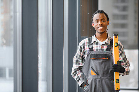 Smiling handyman holding a spirit level, symbolizing precision and quality in construction workの写真素材