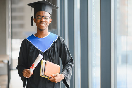 Happy african american university student celebrating graduation, proudly holding a diploma and...