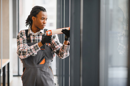 Technician in work attire using a tool to repair an air conditioning unit, focusing on ventilation and maintenance tasksの写真素材