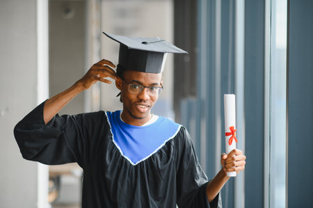 Young man celebrating graduation, adjusting his mortarboard, and proudly holding his diploma,...