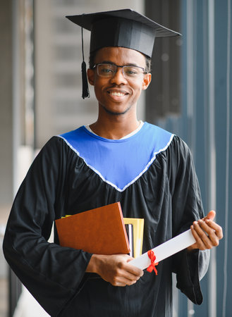 Young doctor celebrating graduation holding his diploma and books, smiling and wearing his...