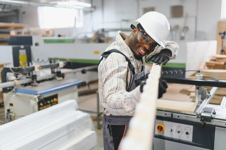 Smiling african american carpenter examining a wooden plank while working in a bustling furniture...