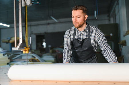 Carpenter preparing material for processing on a cnc machine in a furniture factory, focusing on...