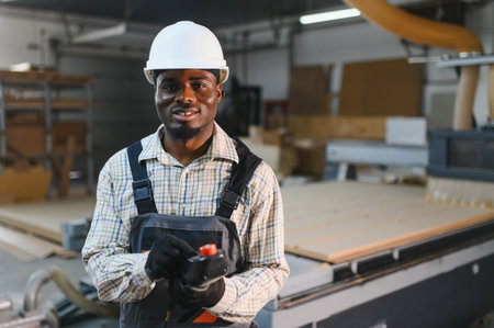 Skilled carpenter controlling a cnc machine in a furniture factory, highlighting modern manufacturing processesの写真素材
