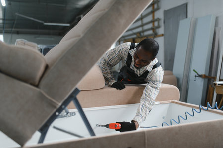 African american worker using a power tool to assemble a sofa in a furniture factory, showcasing the precision and skill in modern furniture productionの写真素材