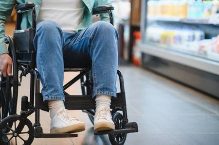 Low section of man using wheelchair buying groceries in supermarket, accessible shopping and...
