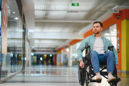 Person using wheelchair moving in shopping mall corridor, representing independent mobility and...