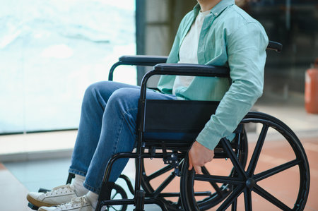 Person with disability navigating a modern building in a wheelchair, symbolizing mobility and accessibility in public spacesの写真素材