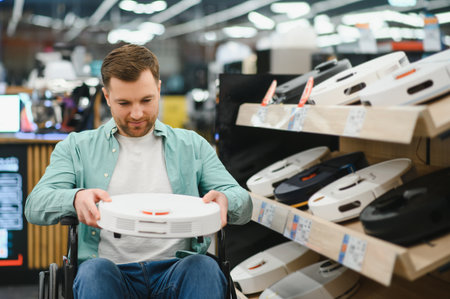 Man in wheelchair choosing robot vacuum cleaner in home appliance store, exploring innovative...