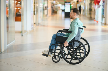 Customer using wheelchair moving in shopping center corridor, enjoying accessibility and independenceの写真素材